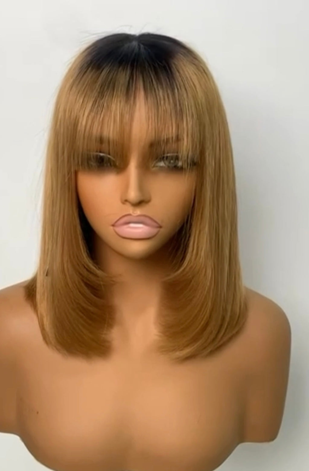 Honey-blonde ombre with dark roots, shoulder-length with bangs.