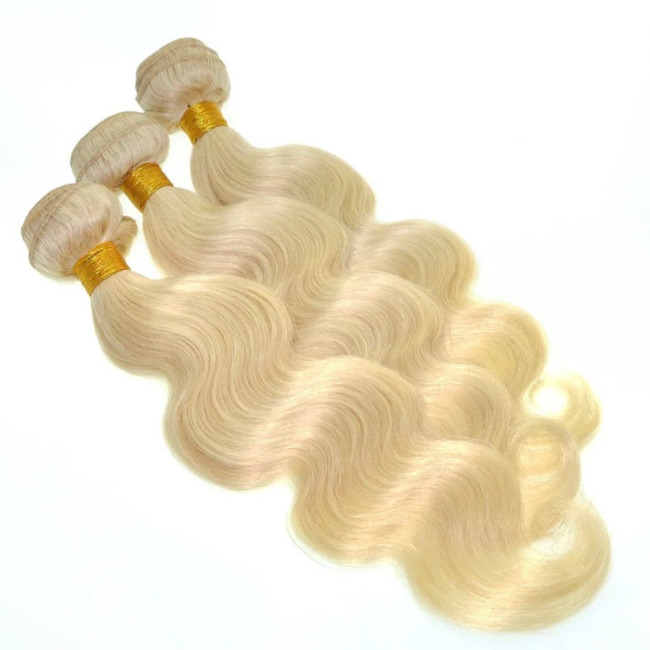 Three bundles of 613 platinum blonde body wave virgin human hair on white background