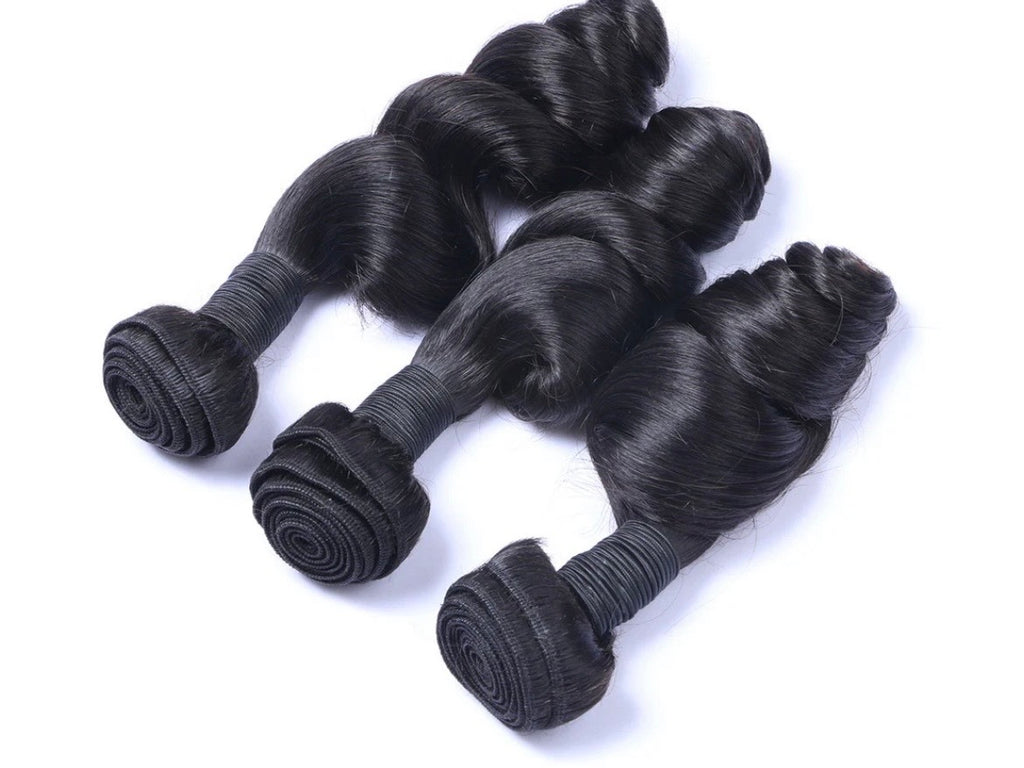 Three bundles of black hair extensions on a white background