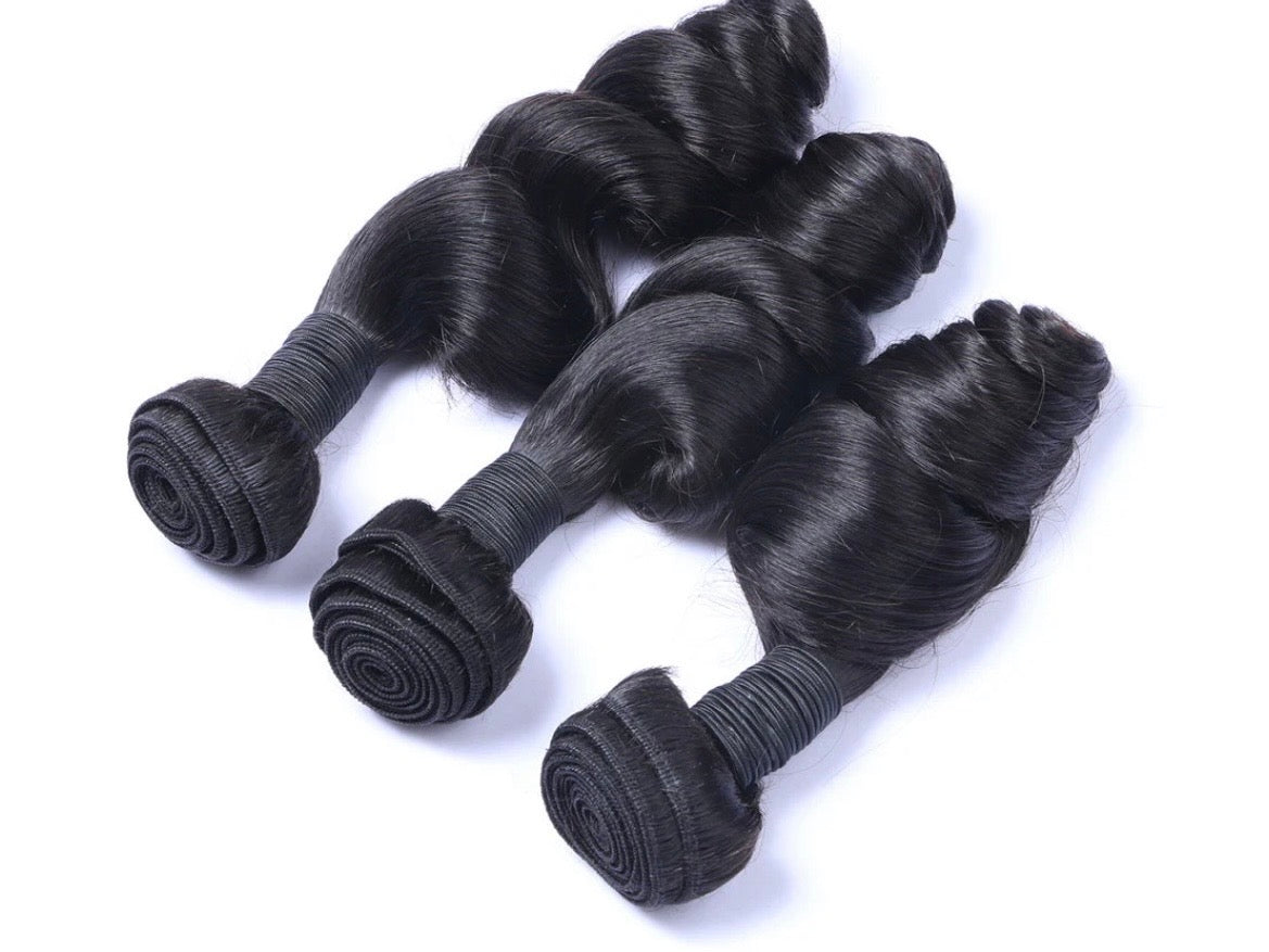 Three bundles of black hair extensions on a white background