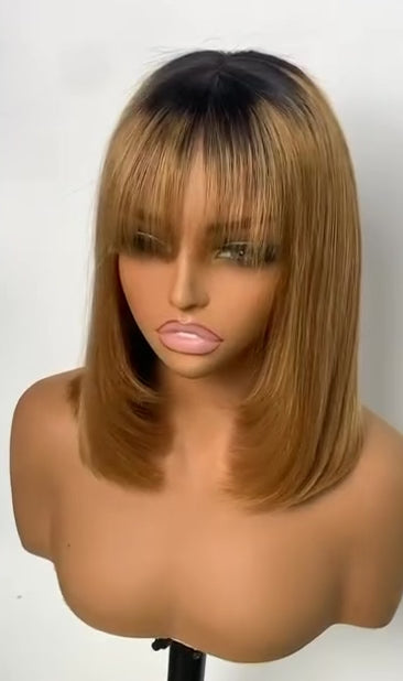 Honey-blonde ombre with dark roots, shoulder-length with bangs.